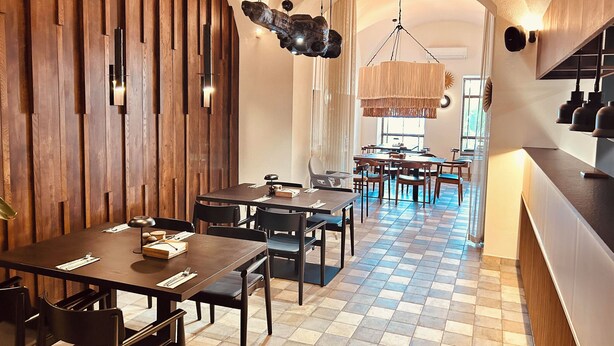 Un restaurant aux murs lambrés, au sol à carreaux et doté d’un espace central où sont disposées des tables et des chaises.