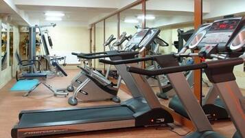 Un gimnasio con cintas de correr, bicicletas estáticas y máquinas de pesas.