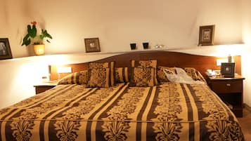 A neatly made bed with a floral-patterned bedspread, a bedside lamp, and a small potted plant on the nightstand.