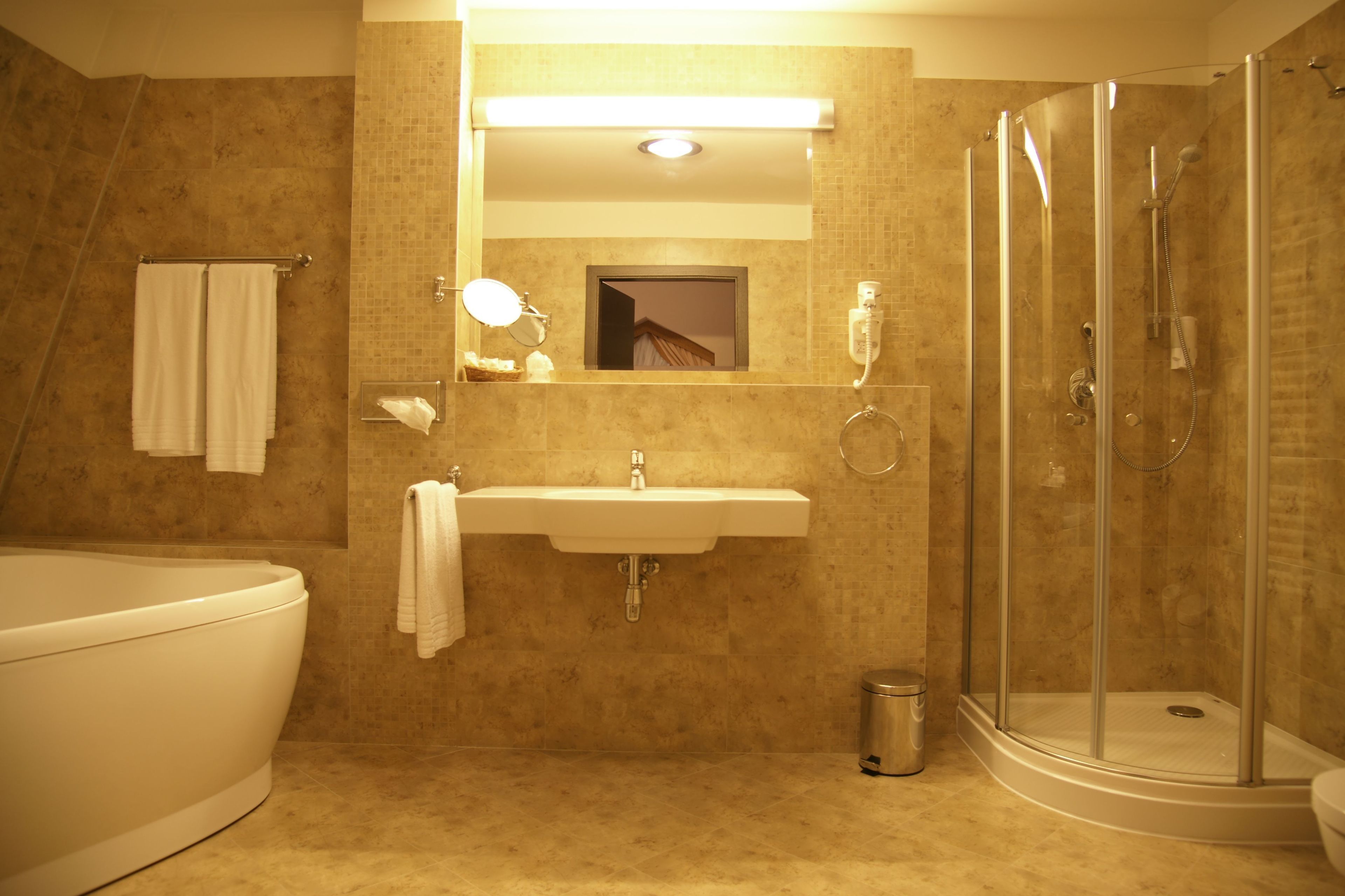Un baño con bañera, lavabo, espejo y ducha con mampara de vidrio.