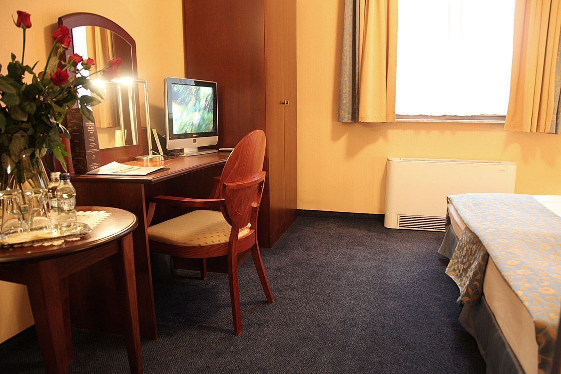Une chambre d’hôtel équipée d’un bureau, d’une chaise, d’un ordinateur, d’un lit et d’une fenêtre avec des rideaux.