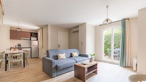 A modern apartment with a dining area, a grey sofa, and a large window with curtains. - Appart'City  Classic Toulouse Colomiers (Colomiers)