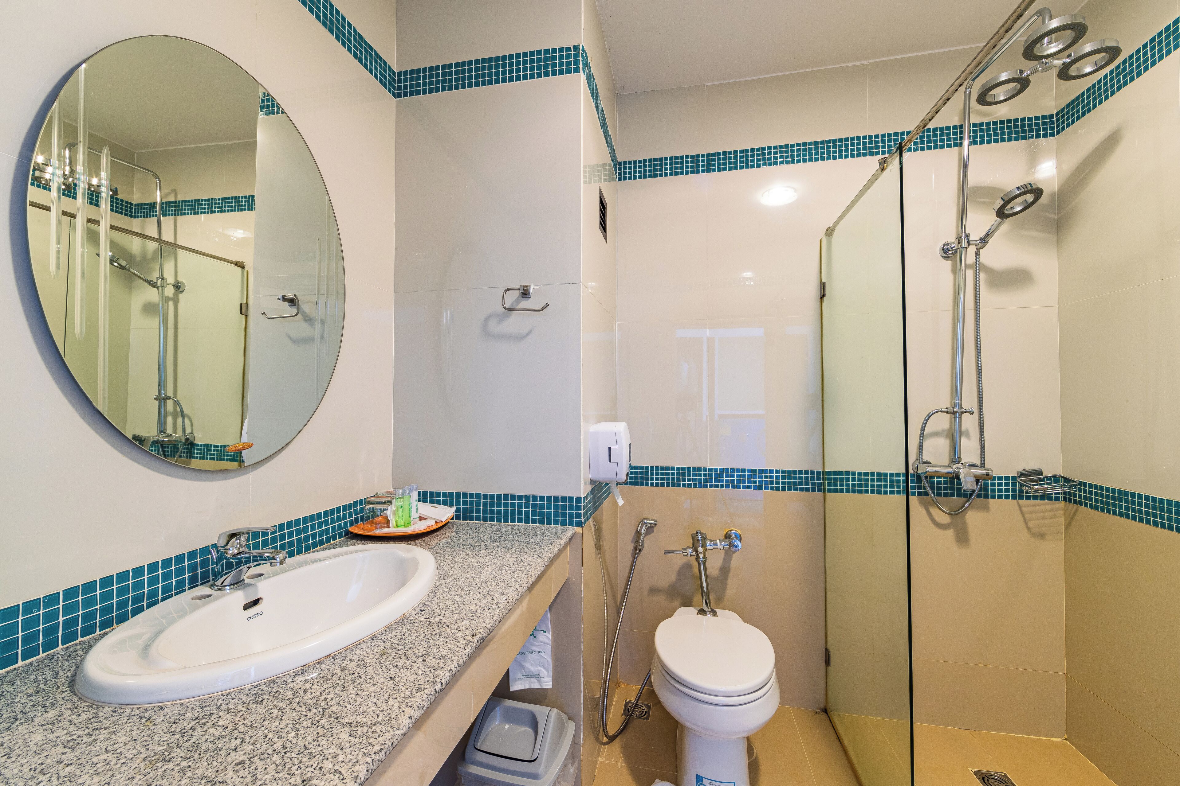 Een badkamer met een witte wastafel, een spiegel, een toilet en een douchecabine met glazen wanden.