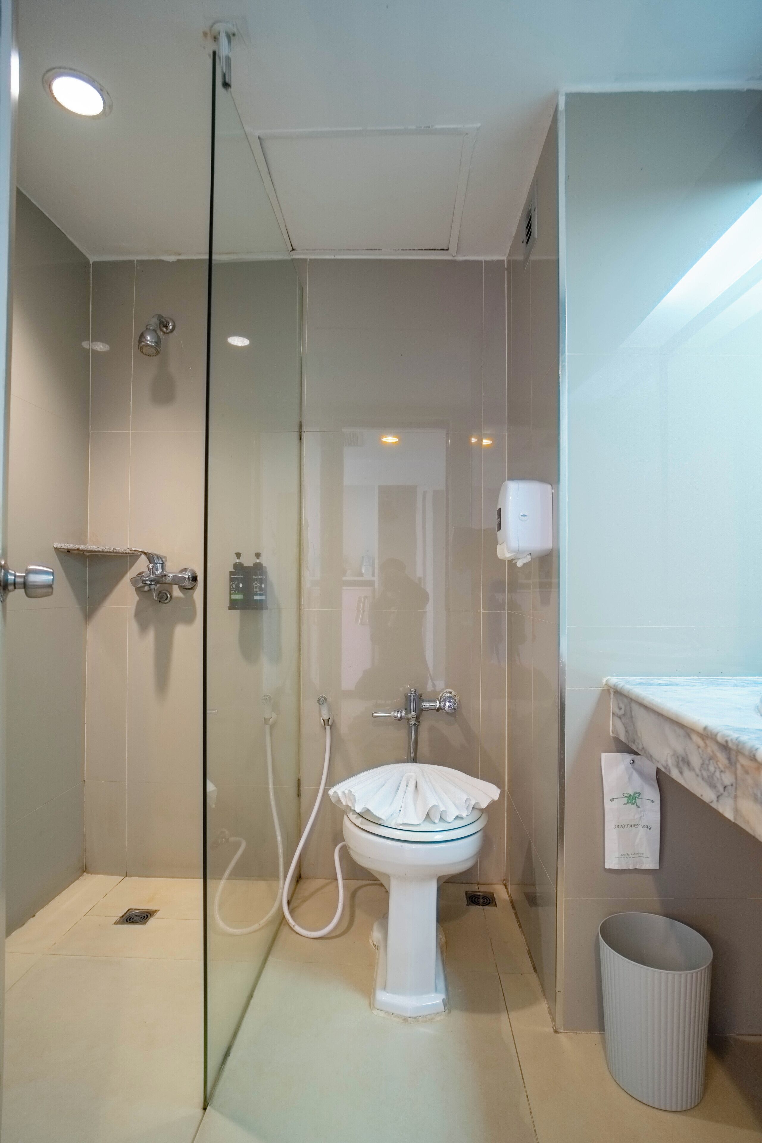 A modern bathroom with a glass-enclosed shower, a white pedestal sink, and a marble countertop.
