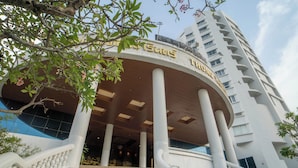 A hotel entrance with a curved facade, multiple columns, and a staircase leading up to the entrance. - Thong Tarin Hotel (Surin)