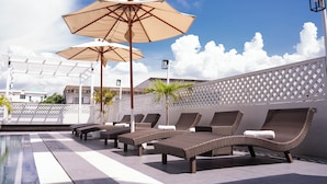 A rooftop pool area with lounge chairs and umbrellas. - Thong Tarin Hotel (Surin)