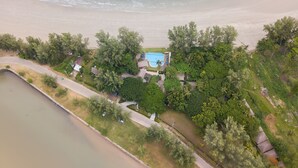 An aerial view of a beachfront property with a swimming pool, surrounded by lush greenery and a sandy beach. - Twin Bay Resort (Ko Lanta)