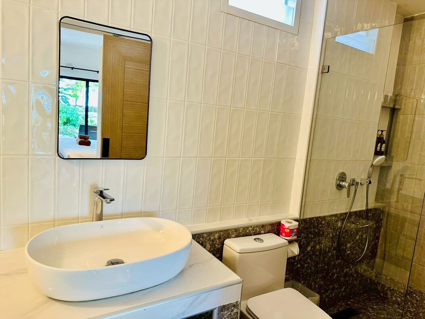 Een badkamer met een wit wastafelmeubel, een toilet en een douchecabine van glas.
