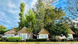 A row of thatched-roof cottages with a sandy beach in the foreground. - Twin Bay Resort (Ko Lanta)