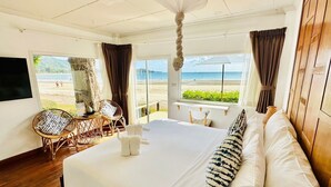 A hotel room with a large bed, a view of the beach, wicker furniture, and a ceiling fan. - Twin Bay Resort (Ko Lanta)