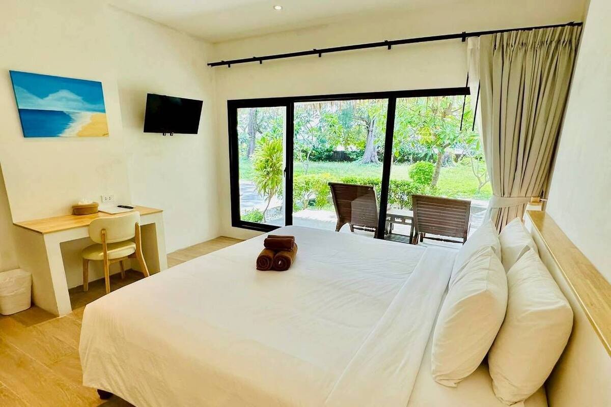 A spacious bedroom with a large bed, a desk, and a TV.