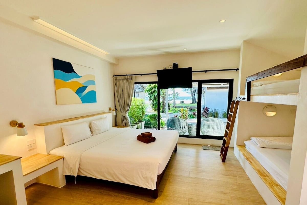 A hotel room with a large bed, a desk, a TV, and a balcony with a view.