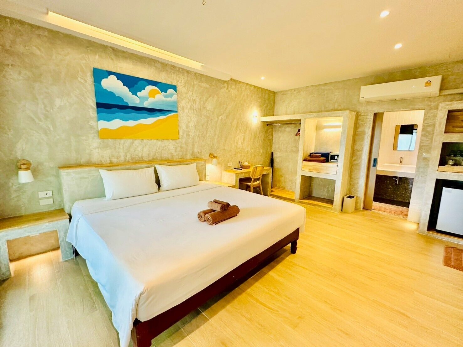 A hotel room with a large bed, a desk, and a bathroom visible through an open door.