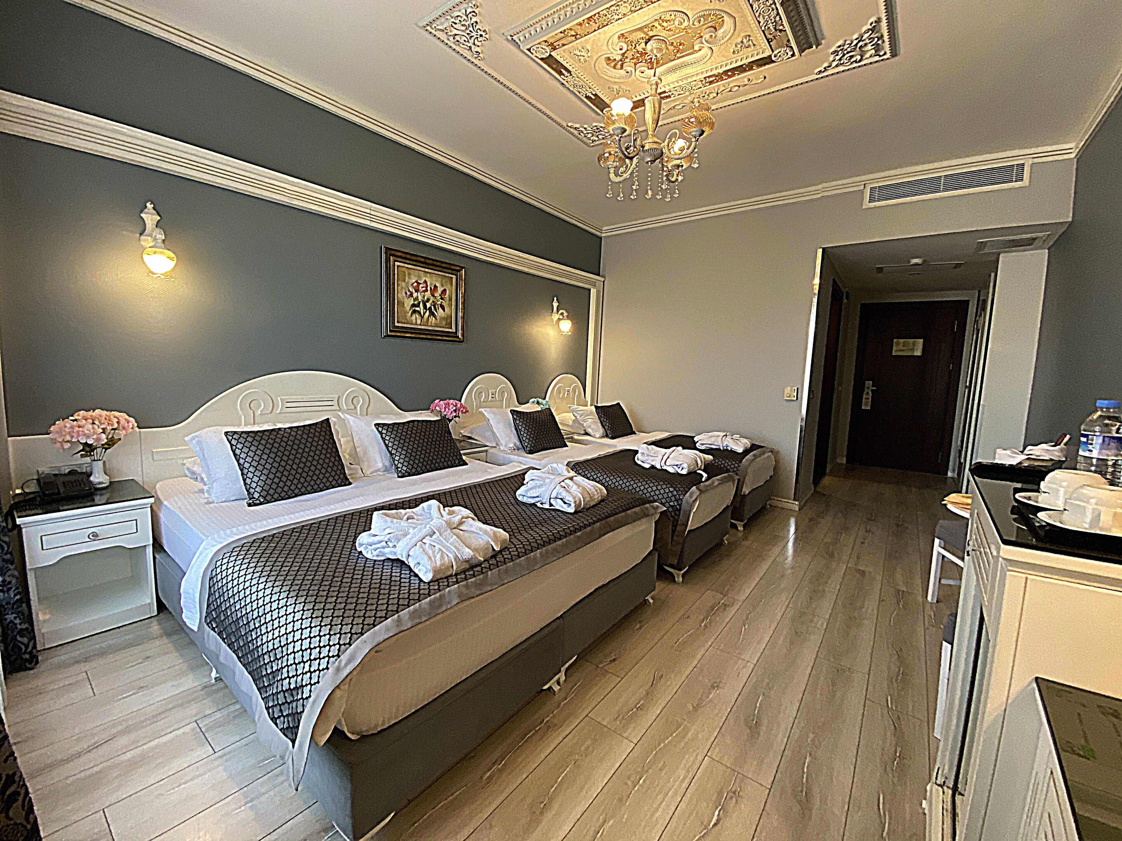 Une chambre d’hôtel avec un grand lit, deux tables de chevet, un bureau et un lustre.