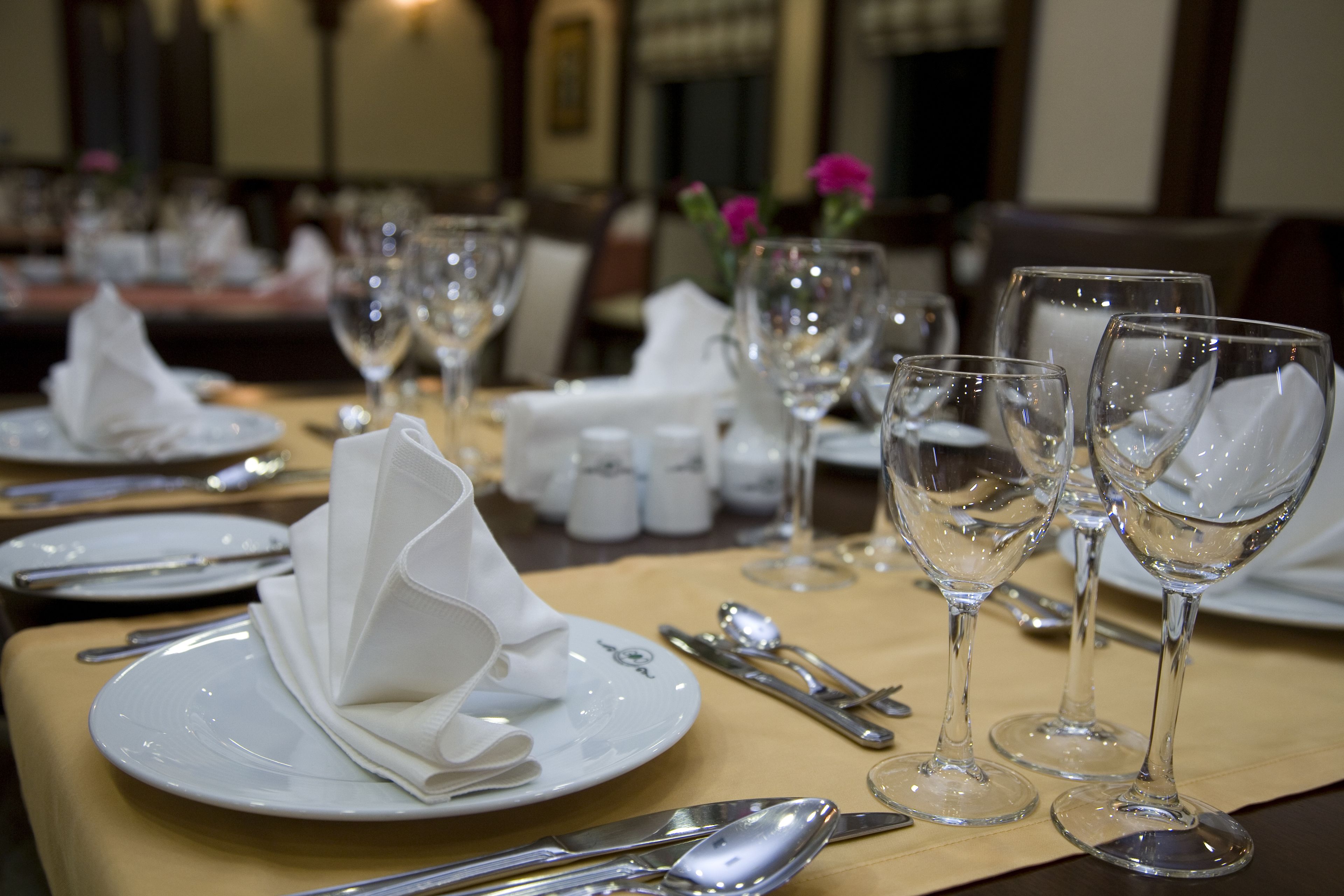 A dining table set with plates, cutlery, and wine glasses, indicating a formal dining arrangement.