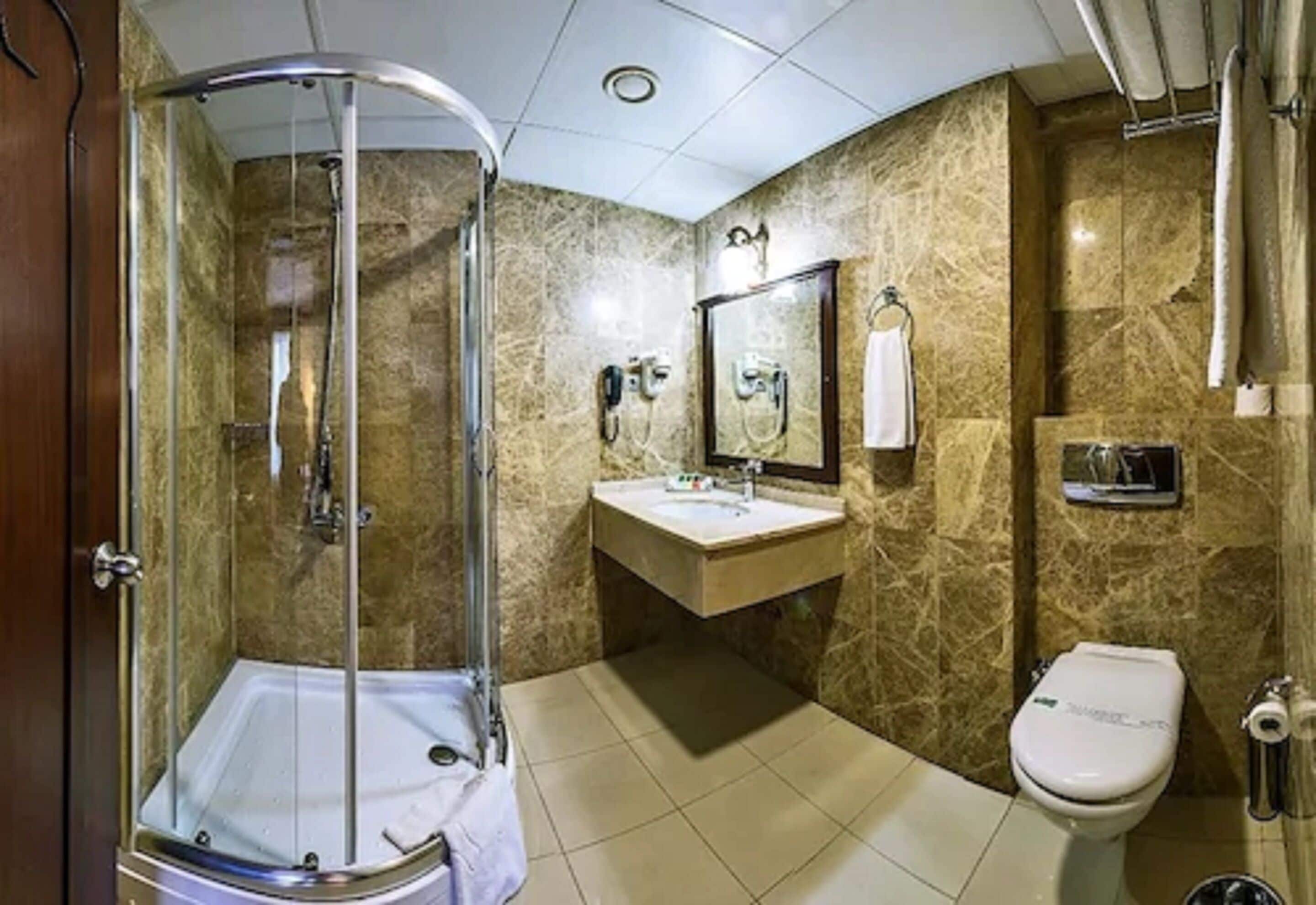 Une salle de bain avec une douche à parois de verre, un lavabo, des toilettes et un miroir.