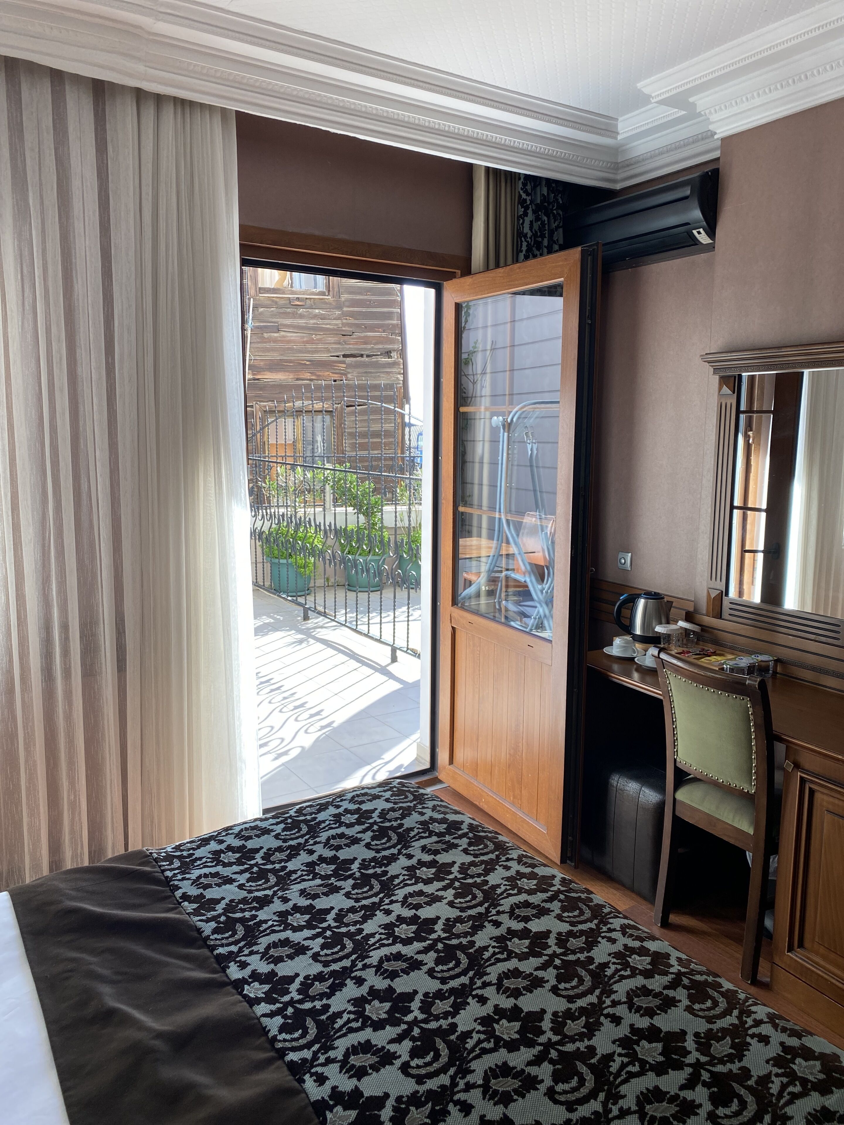 Une chambre d’hôtel équipée d’un lit, d’un bureau, d’une chaise, d’une grande fenêtre et d’une porte donnant sur un balcon.
