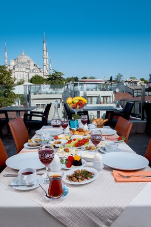 Una mesa de comedor dispuesta con diferentes platos, bebidas y una vista de una mezquita al fondo.