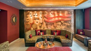 A modern living room with a curved sofa, a coffee table, and a decorative wall with circular patterns. - Ferman Hotel Old City - Special Class (Istanbul)