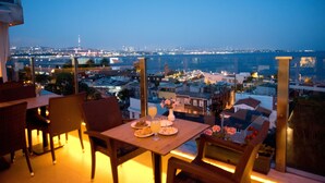A terrace with a table set for dining, overlooking a cityscape and body of water at dusk. - Ferman Hotel Old City - Special Class (Istanbul)