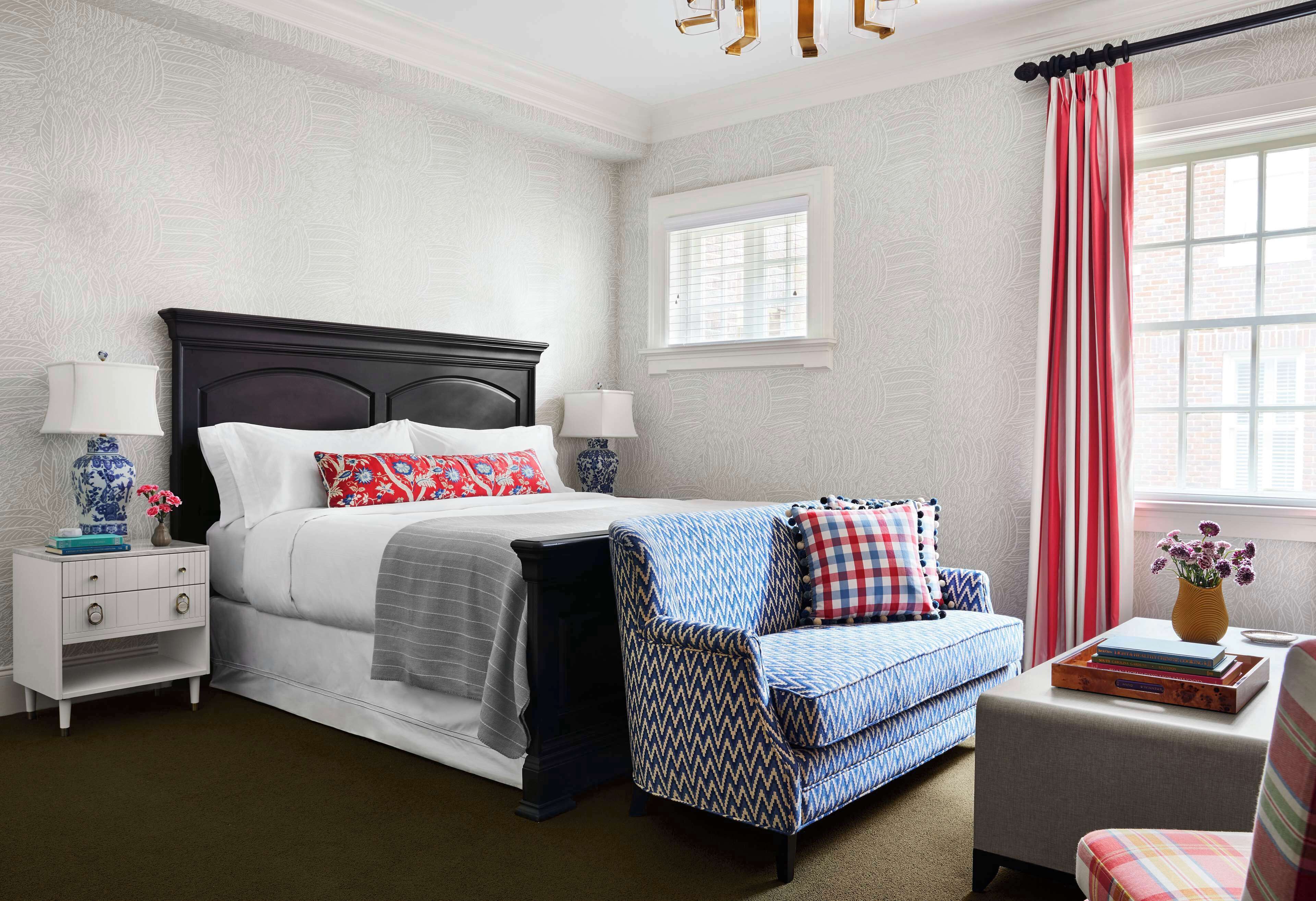 A bedroom with a bed, nightstand, chair, and a window with curtains.