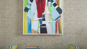 A room with a green sofa, a colorful abstract painting, and a patterned rug.
