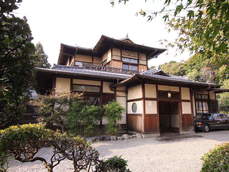 Um edifício japonês tradicional com telhado de telhas, vigas de madeira e um pátio de cascalho.