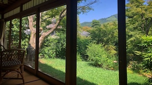 A room with large windows, a wooden ceiling, and a wicker chair.