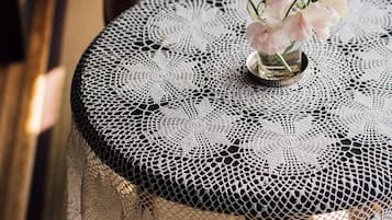 A round table with a lace tablecloth and a vase with flowers.