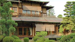 A traditional Japanese building with a wooden exterior, a stone pathway, and well-maintained greenery.