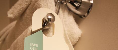 A tag attached to a towel with a message about saving the planet by choosing to reuse towels.