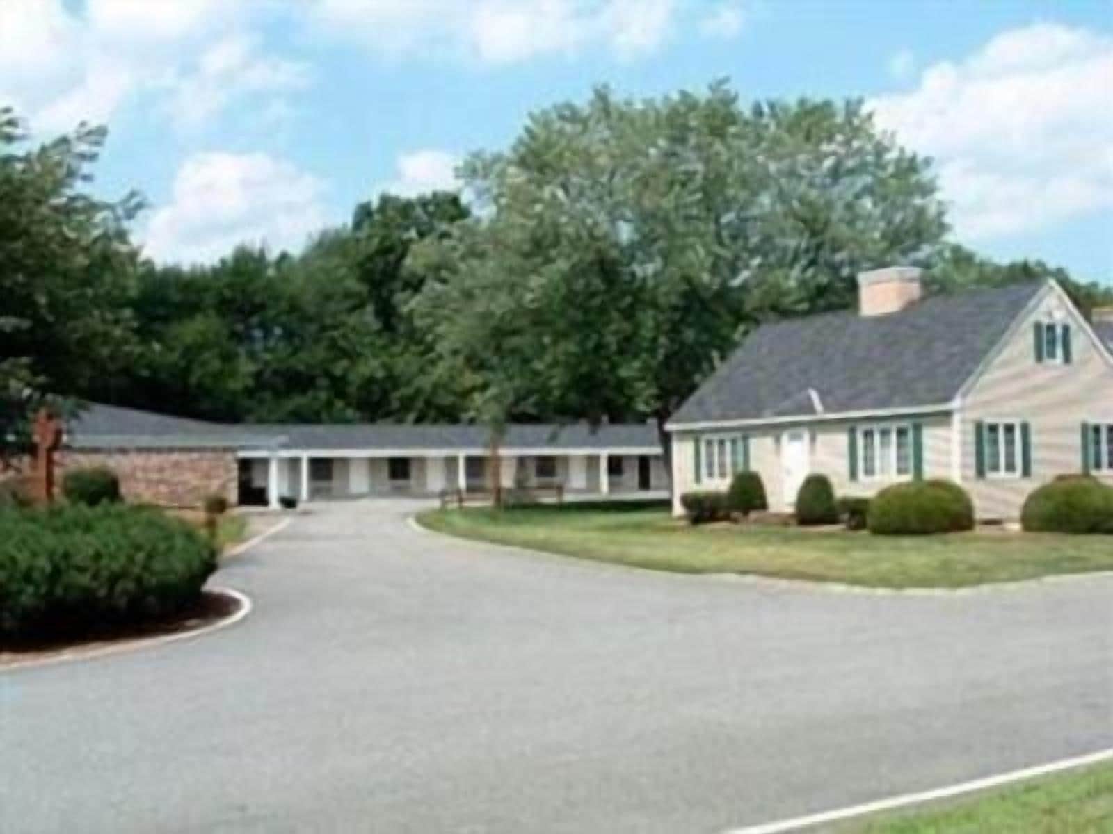A two-story building with a central entrance, surrounded by a paved driveway and landscaped areas.