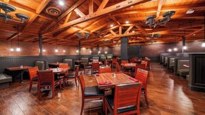 A restaurant with wooden beams, brick walls, and multiple seating areas.