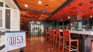 A bar area with wooden ceiling, red chairs, and a bar counter.