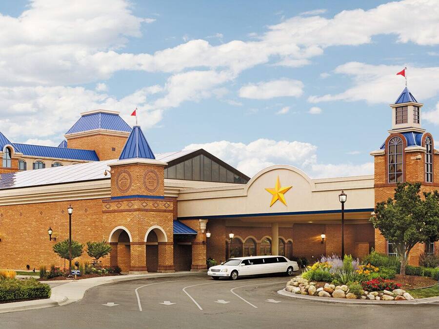 A hotel with a star emblem, a parking lot, and a white car parked in front.