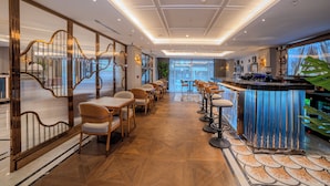 A modern bar area with a long counter and high stools, surrounded by tables and chairs. - Grand Hilarium Hotel (Istanbul)