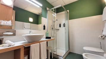 A bathroom with a large sink, a glass-enclosed shower, and a toilet.
