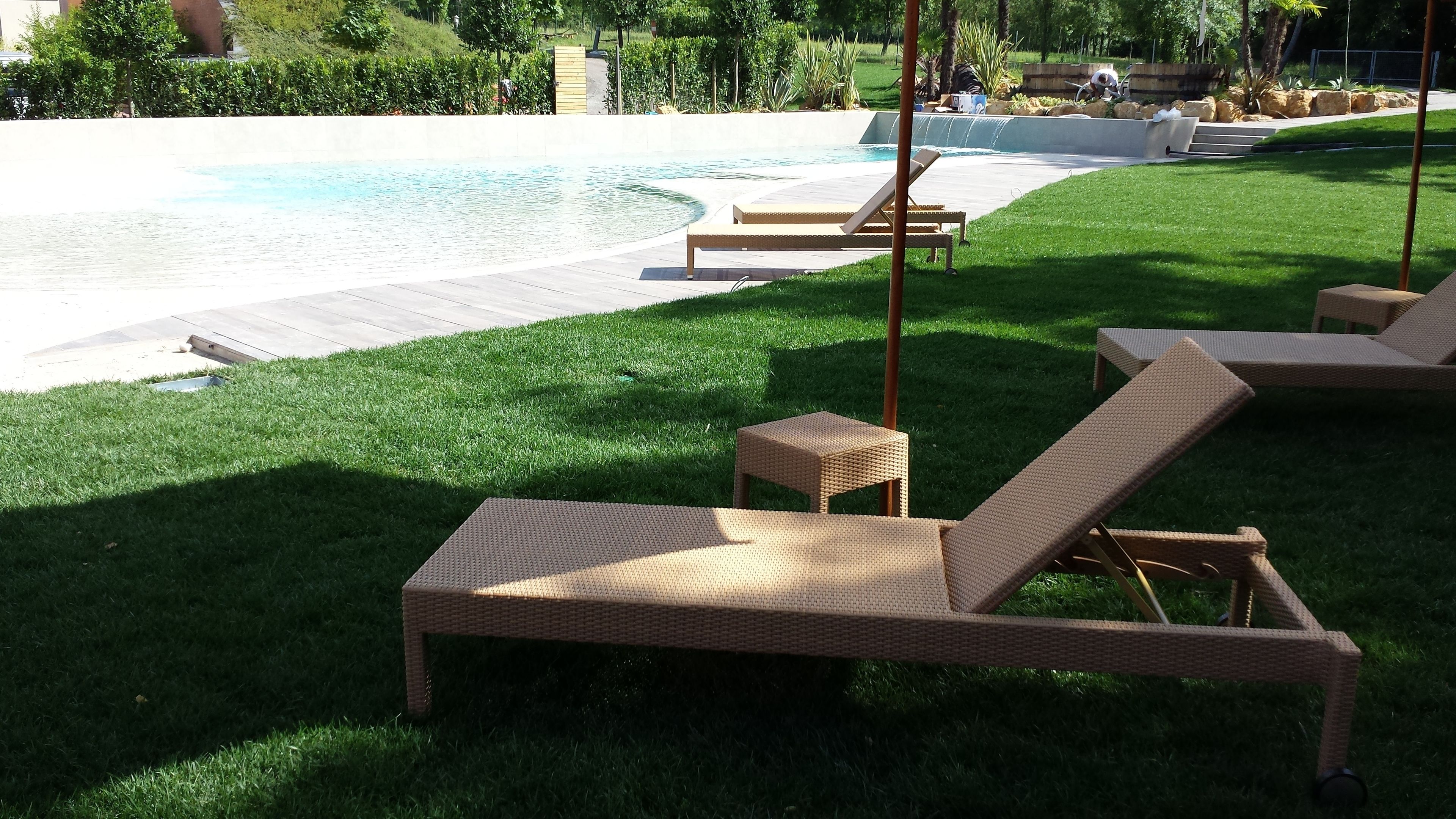 A pool area with lounge chairs and a small table.