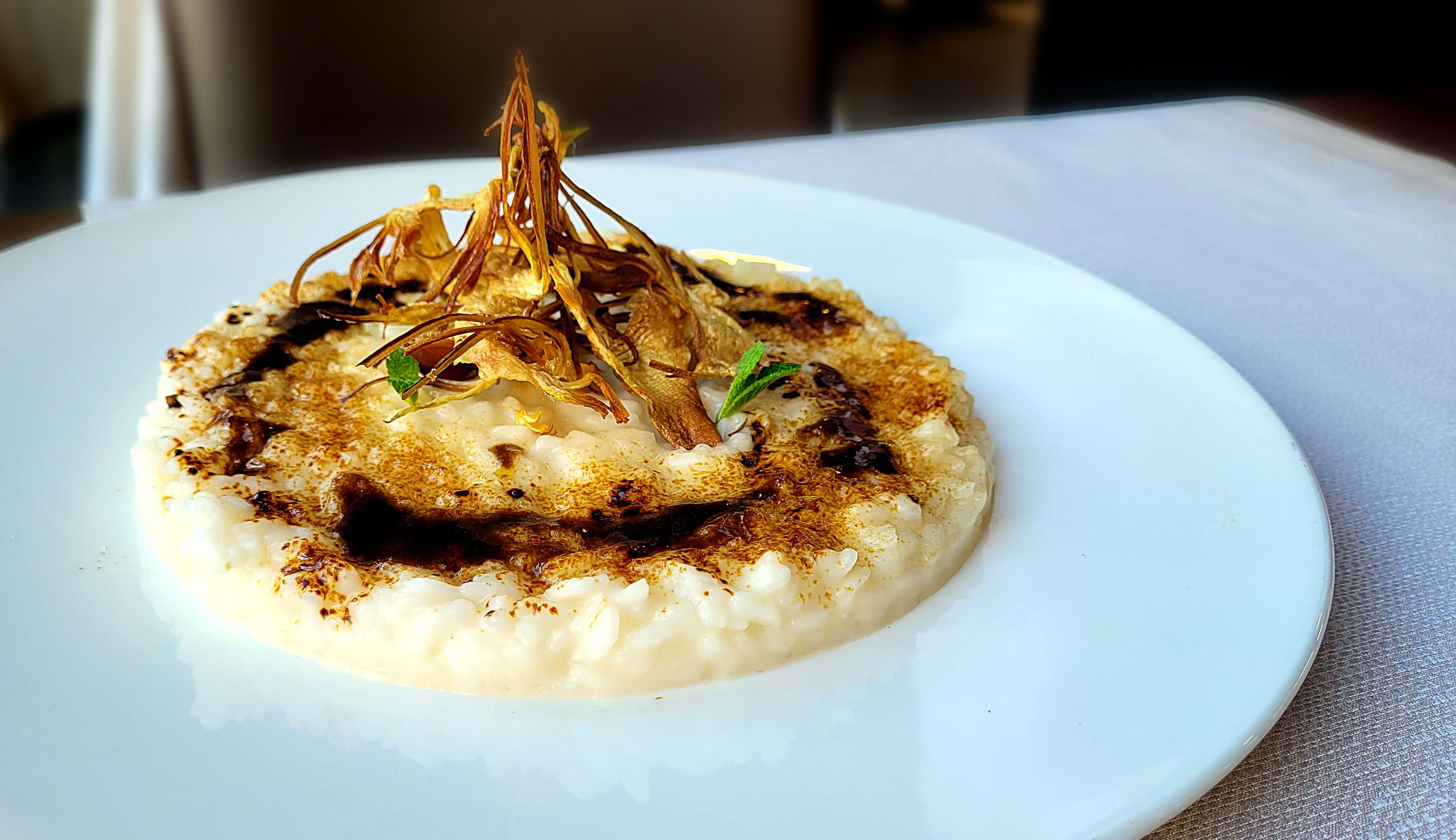Ein Teller Essen mit einer cremigen Soße, bedeckt mit karamellisierten Zwiebeln und Kräutern.