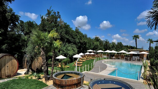Un espace piscine agrémenté de barils en bois, de chaises longues et de parasols.
