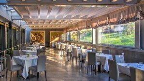 Un restaurant spacieux, doté de nombreuses tables et chaises, de grandes fenêtres avec des rideaux et d’un aménagement intérieur moderne.