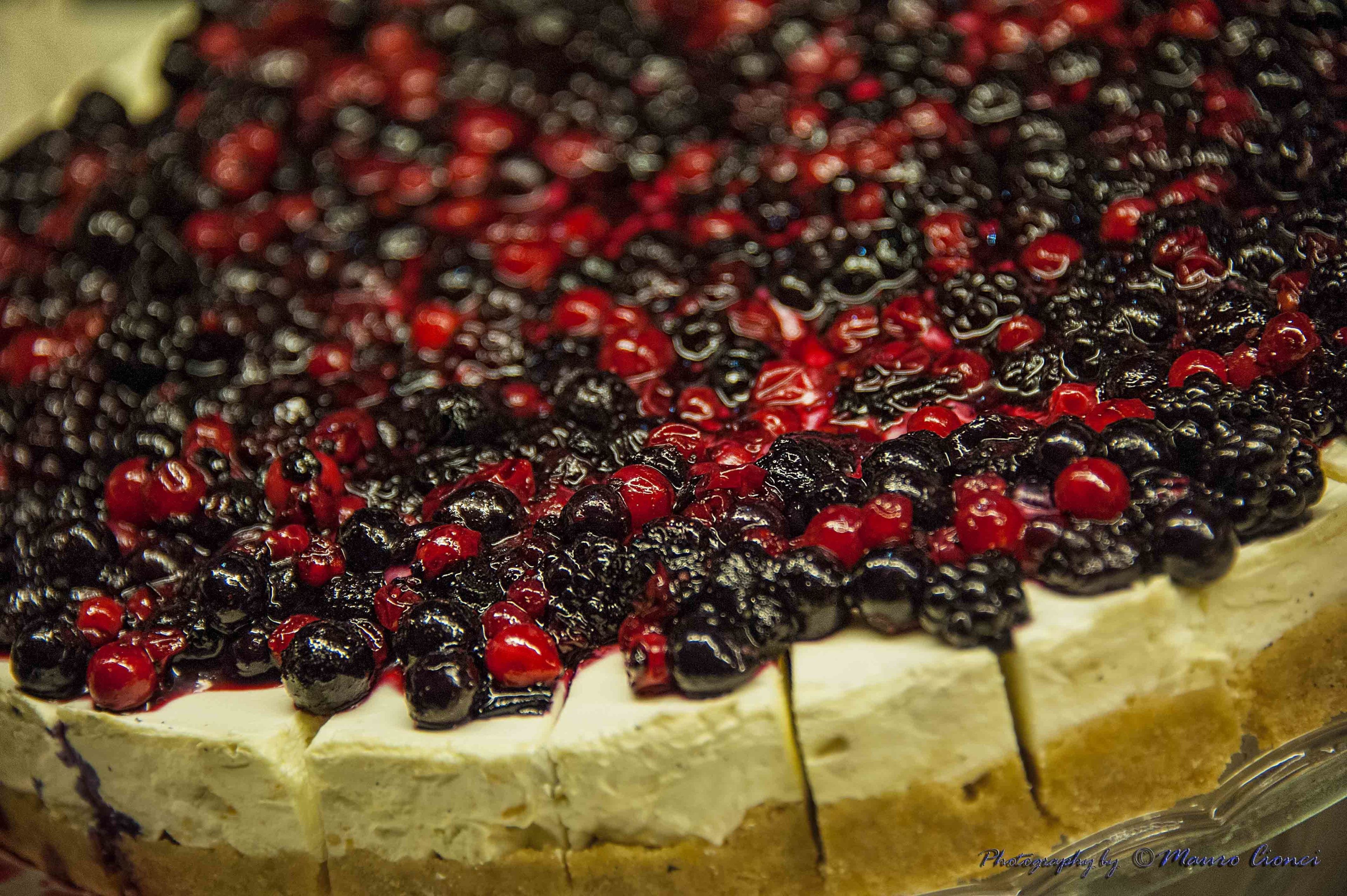 A close-up of a dessert with a creamy base and a topping of mixed berries.