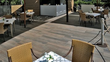Eine Außenpatio mit Tischen und Stühlen, ein weißer Empfangstresen und ein Holzzaun.