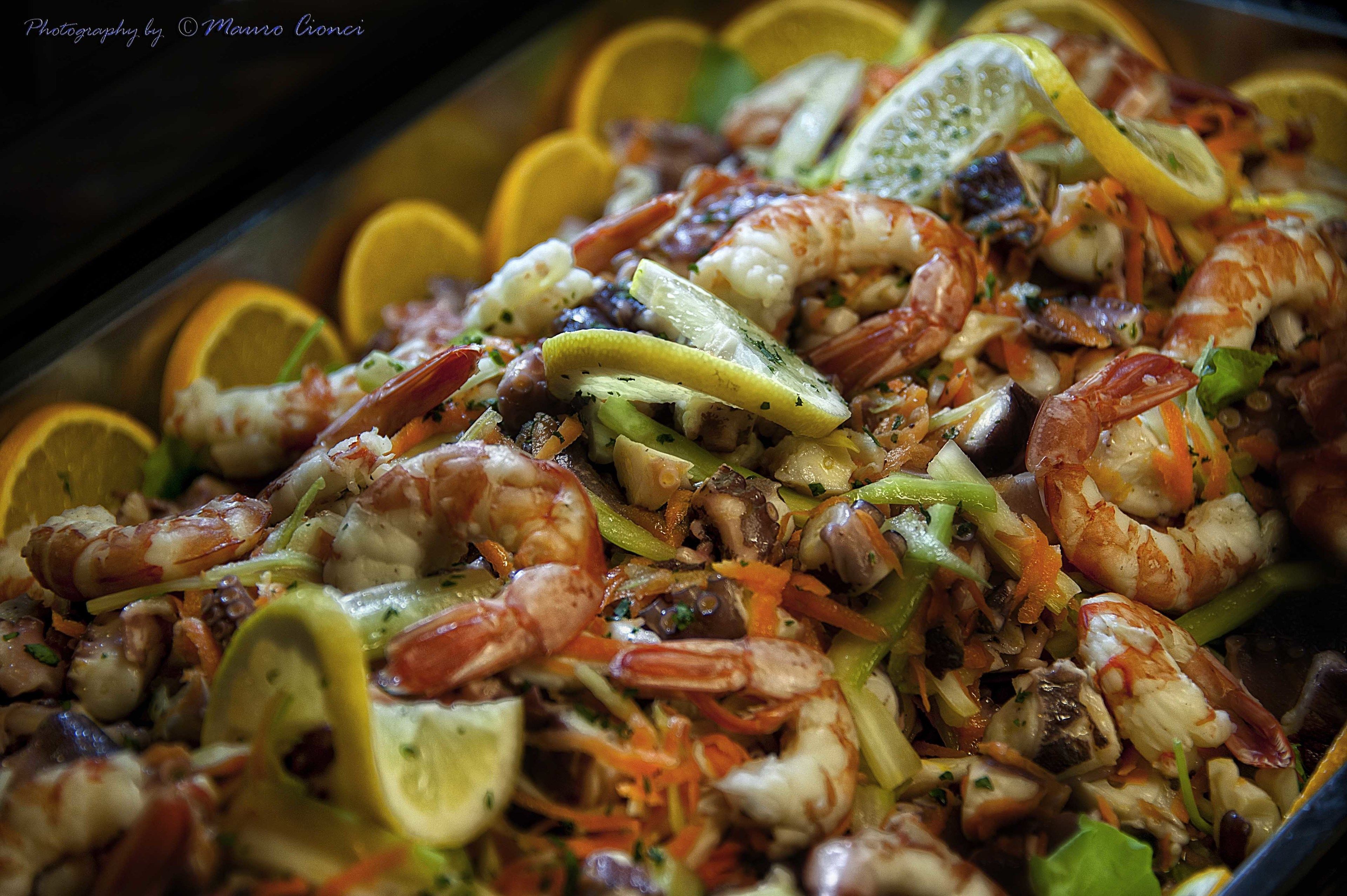 Un plat de fruits de mer composé de crevettes, de légumes et de tranches de citron.