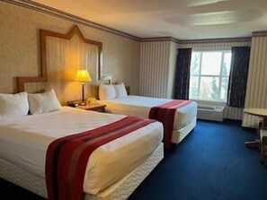 A hotel room with two beds, a desk, a chair, and a window with curtains. - Cactus Petes Resort Casino & Horseshu Hotel (Jackpot)