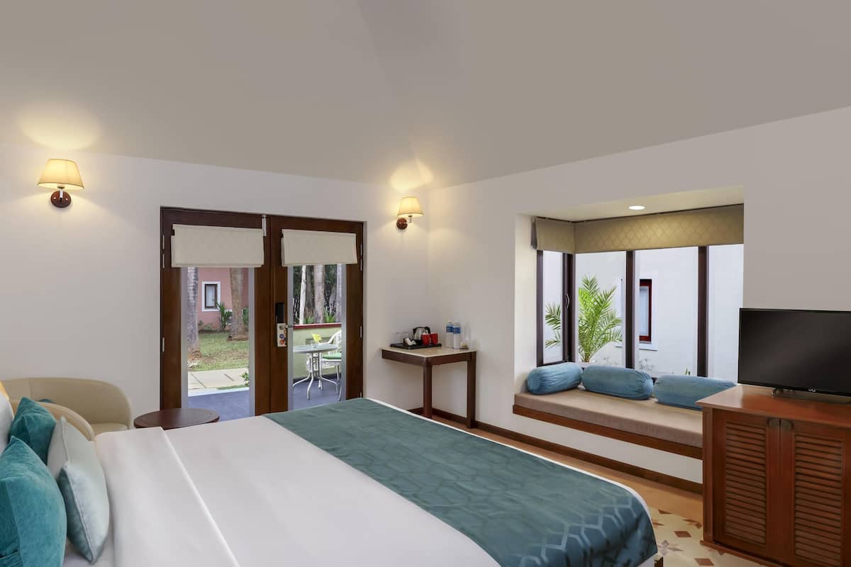 A hotel room with a bed, a TV, a small table, and a window with a view of the outside.