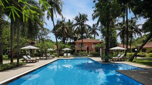 Una piscina al aire libre, sombrillas, sillones reclinables de piscina