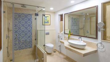 Un baño con ducha de vidrio, inodoro, lavamanos con espejo y una planta decorativa.