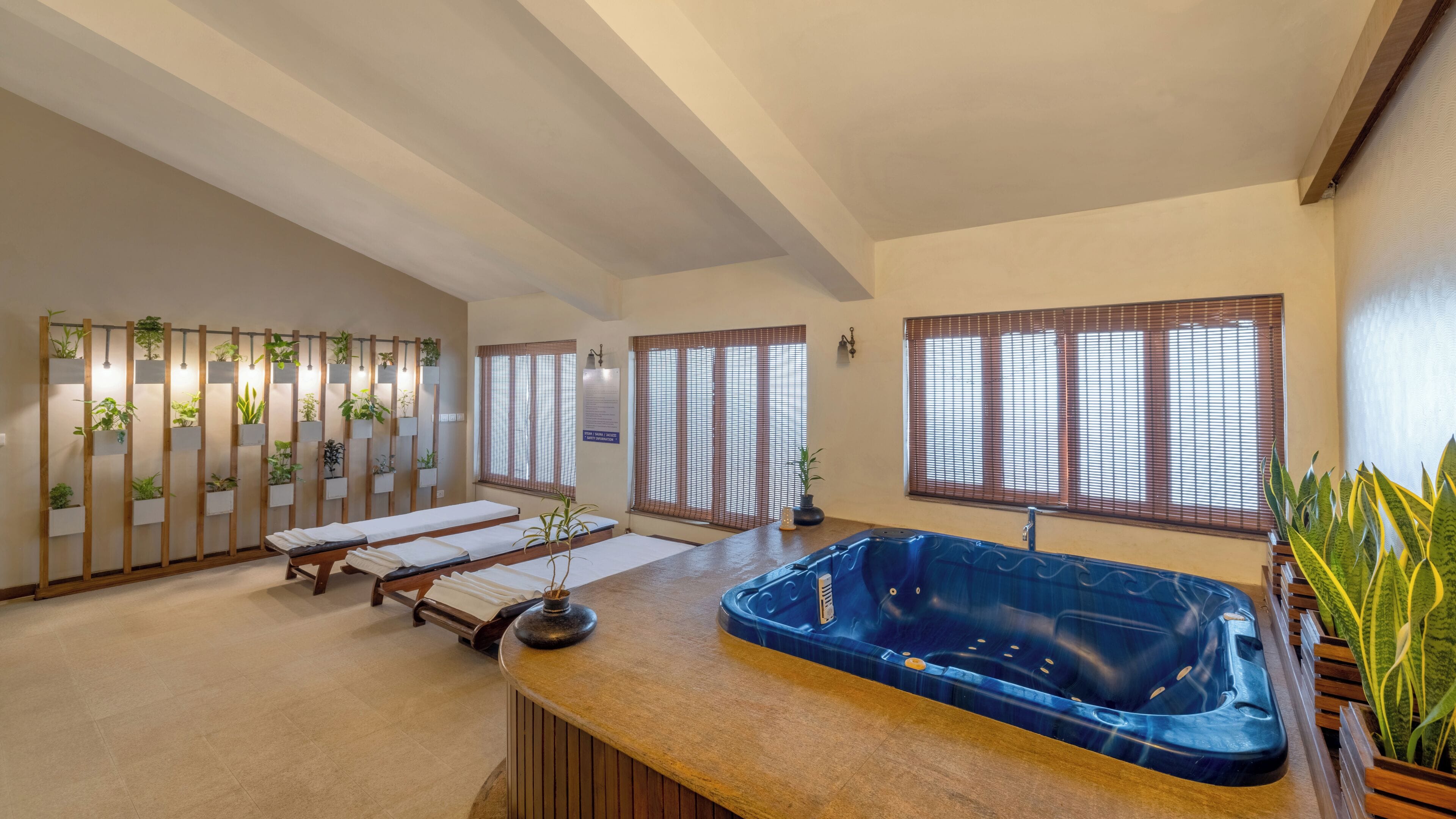 Une salle de spa équipée d’un bain à remous, de bancs en bois et d’un mur agrémenté de plantes en pot.
