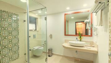 Une salle de bain moderne avec une douche à parois de verre, des toilettes, un lavabo avec un miroir et un porte-serviettes.
